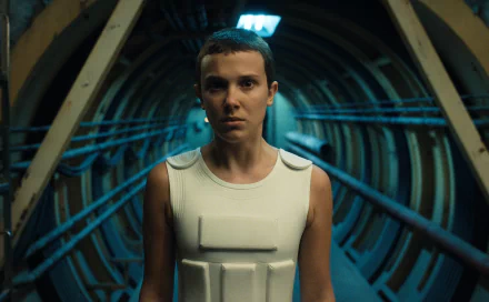 HD desktop wallpaper featuring Millie Bobby Brown as Eleven from the TV show Stranger Things, set against an industrial tunnel background.