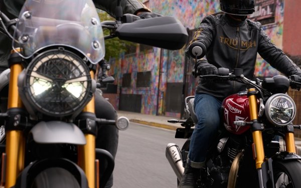 Rider on a Triumph Scrambler 400 X motorcycle cruising through an urban area, perfect as a HD desktop wallpaper and background.