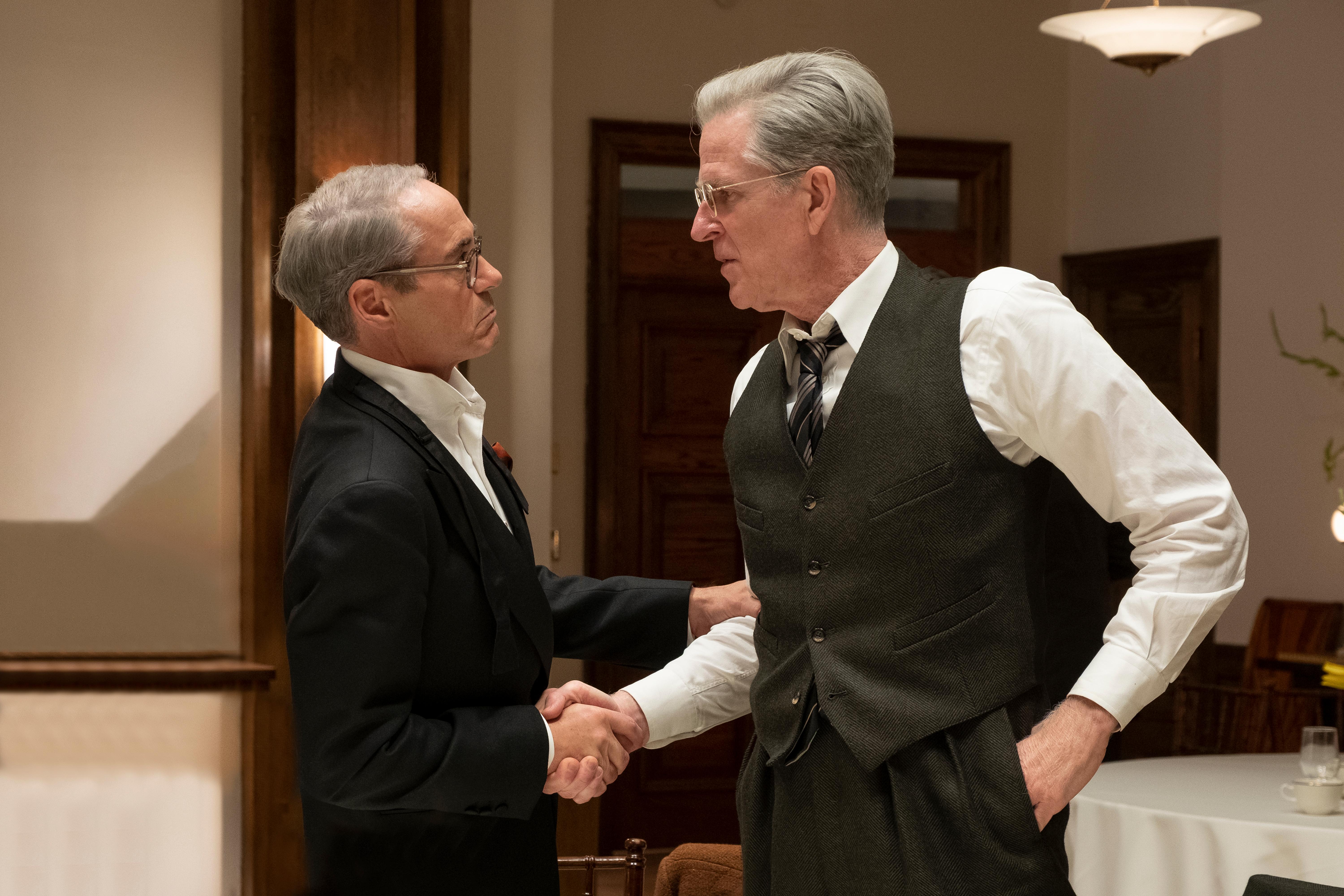 HD desktop wallpaper featuring two actors in character, shaking hands in a period-style setting, tagged with Oppenheimer, Robert Downey Jr., and Matthew Modine.
