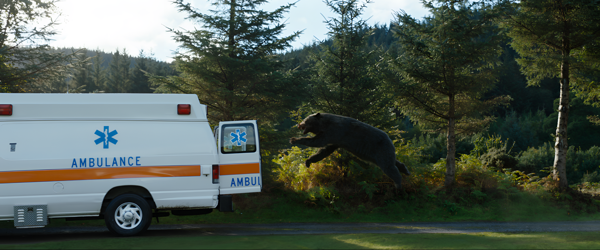 HD desktop wallpaper of the Cocaine Bear leaping near an ambulance in a forested area.