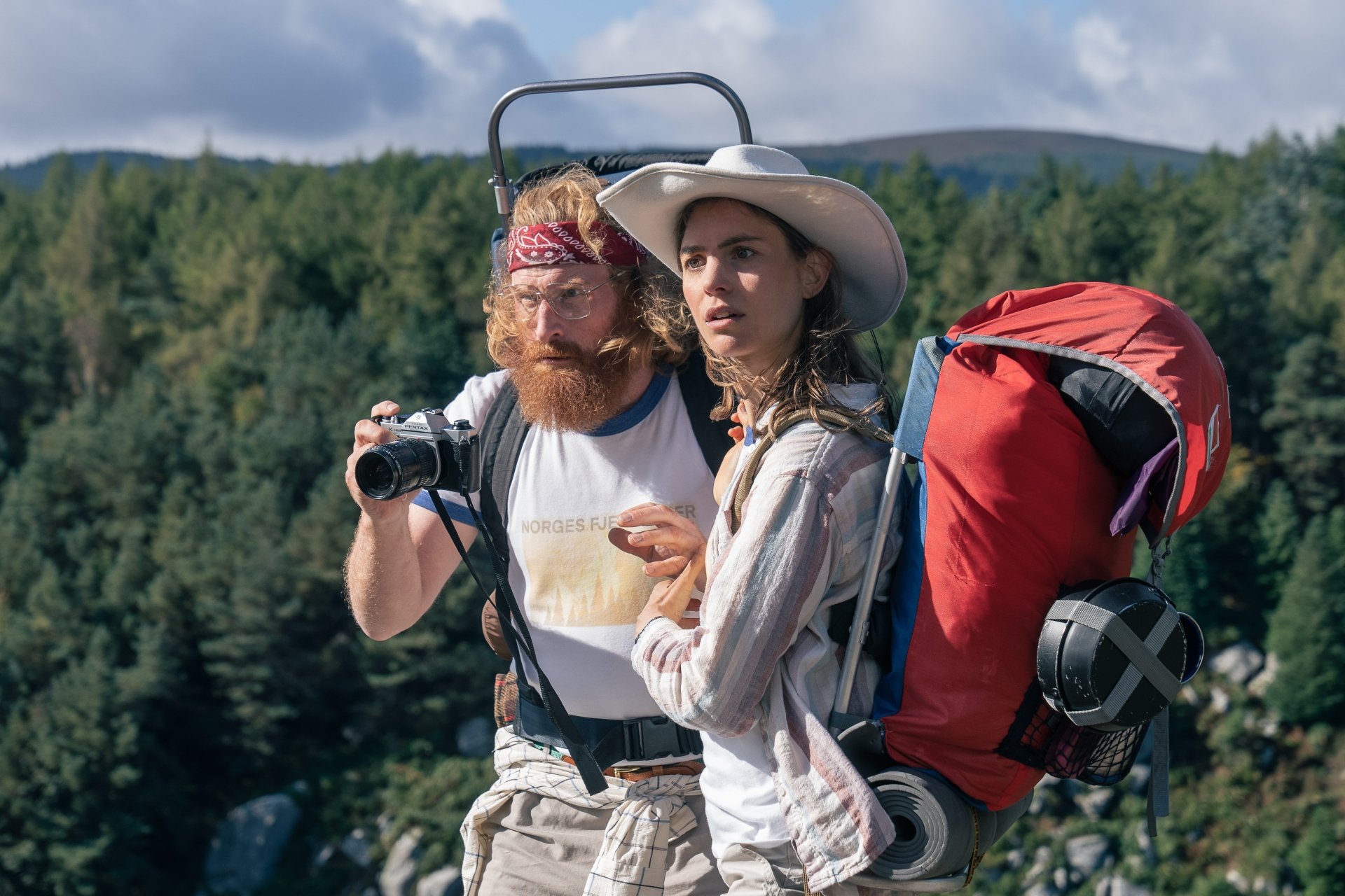 A scene from the movie Cocaine Bear, featuring two hikers against a backdrop of lush greenery, capturing a moment of adventure in this HD desktop wallpaper.