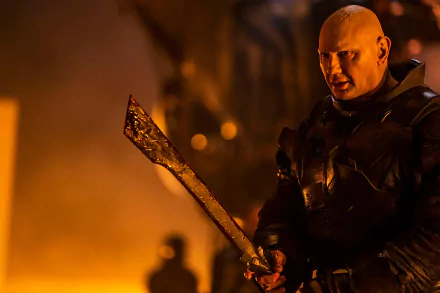 HD wallpaper of a character from Dune: Part Two holding a weapon, with a fiery backdrop evoking the intense atmosphere of the film.