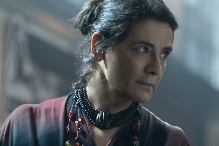 HD desktop wallpaper of a scene from Insidious featuring a concerned-looking character wearing a necklace with red accent beads, set against a dimly lit background, highlighting the suspenseful atmosphere of The Red Door.