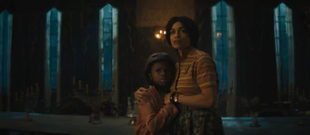 Rosario Dawson hugging a child in a dimly lit, eerie room from the movie Haunted Mansion, suitable as a HD desktop wallpaper.