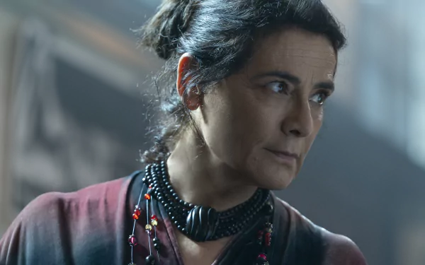 HD desktop wallpaper of a scene from Insidious featuring a concerned-looking character wearing a necklace with red accent beads, set against a dimly lit background, highlighting the suspenseful atmosphere of The Red Door.