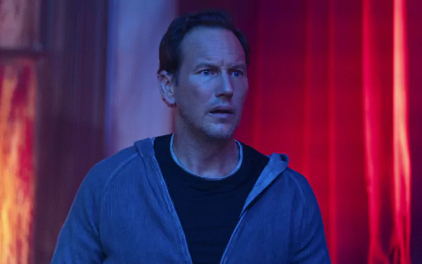 Man in a hoodie looking concerned with a red, eerie glow in the background tagged as 'Insidious: The Red Door' - HD desktop wallpaper.