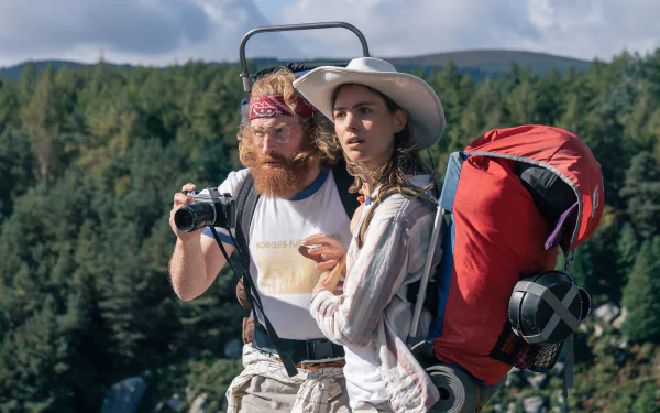 A scene from the movie Cocaine Bear, featuring two hikers against a backdrop of lush greenery, capturing a moment of adventure in this HD desktop wallpaper.