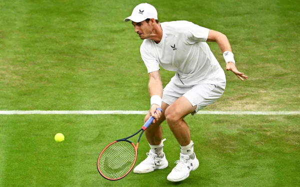 Andy Murray in action during Wimbledon 2023, showcasing his athleticism on the grass court as he prepares to strike the ball in this dynamic tennis scene.