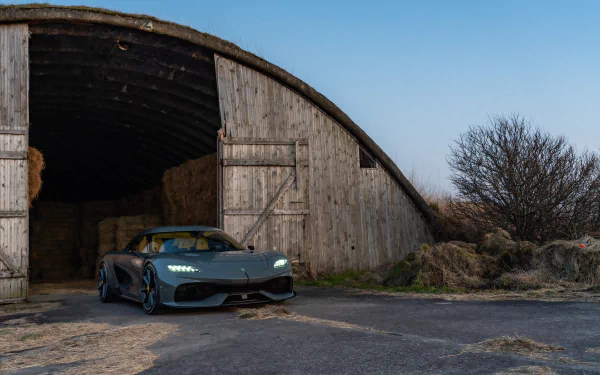 Koenigsegg Gemera parked outside a rustic barn at twilight, HD desktop wallpaper.