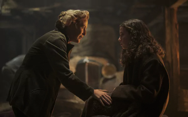 HD wallpaper featuring a dramatic scene with two characters engaging intently, underscored by warm, moody lighting that evokes a sense of intrigue and depth.