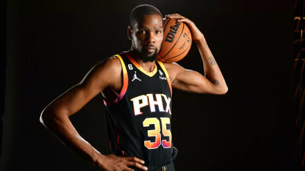 A striking HD wallpaper of Kevin Durant, wearing the Phoenix Suns jersey, poses confidently with a basketball, embodying the spirit of sports and basketball excellence.