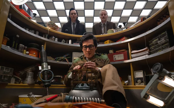 HD desktop wallpaper featuring a scene from the Loki series with characters in an office environment filled with shelves and eclectic items.