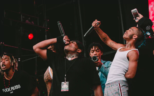 HD PC desktop wallpaper featuring XXXTentacion and fellow musicians performing energetically on stage with microphones in hand.