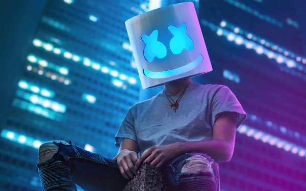 Person wearing a Marshmello head mask sitting in an urban setting at night with city lights in the background, for HD desktop wallpaper.