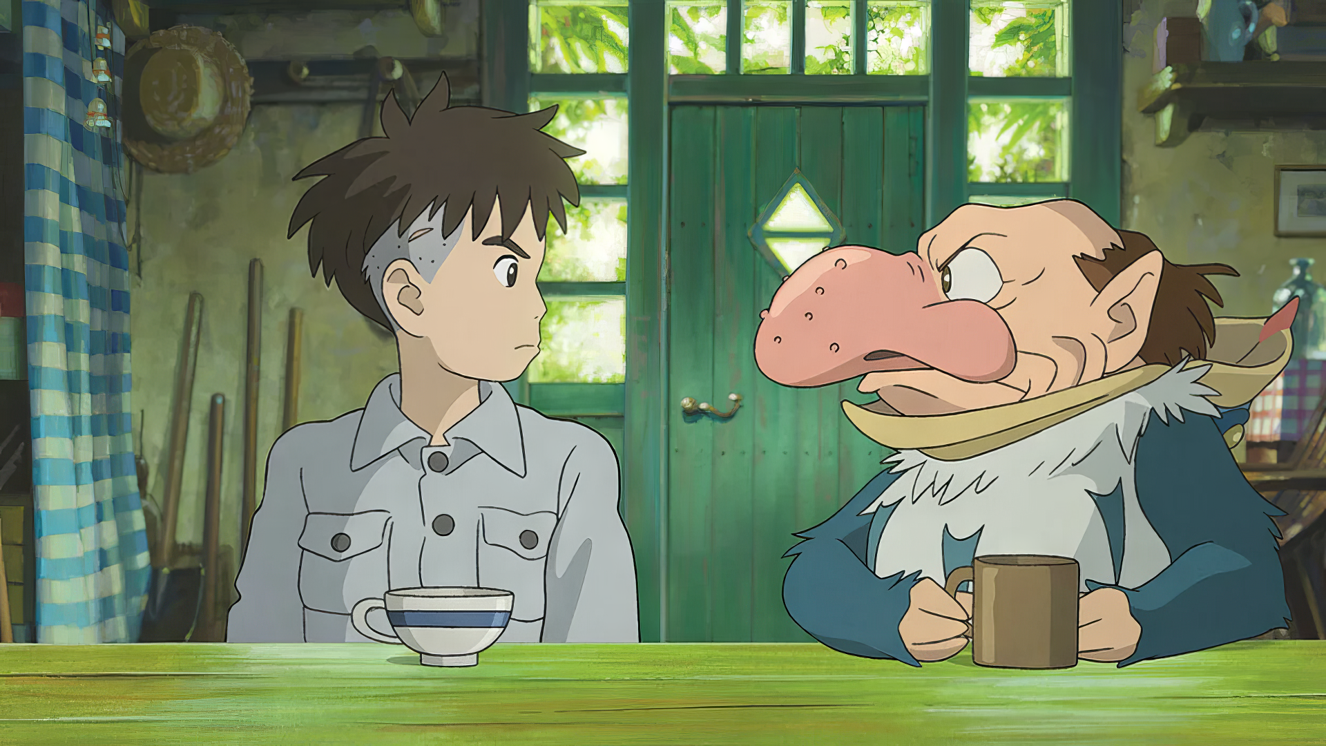 HD desktop wallpaper featuring an animated scene with a young boy and a character with a prominent nose sitting at a table, titled 'The Boy and the Heron'.