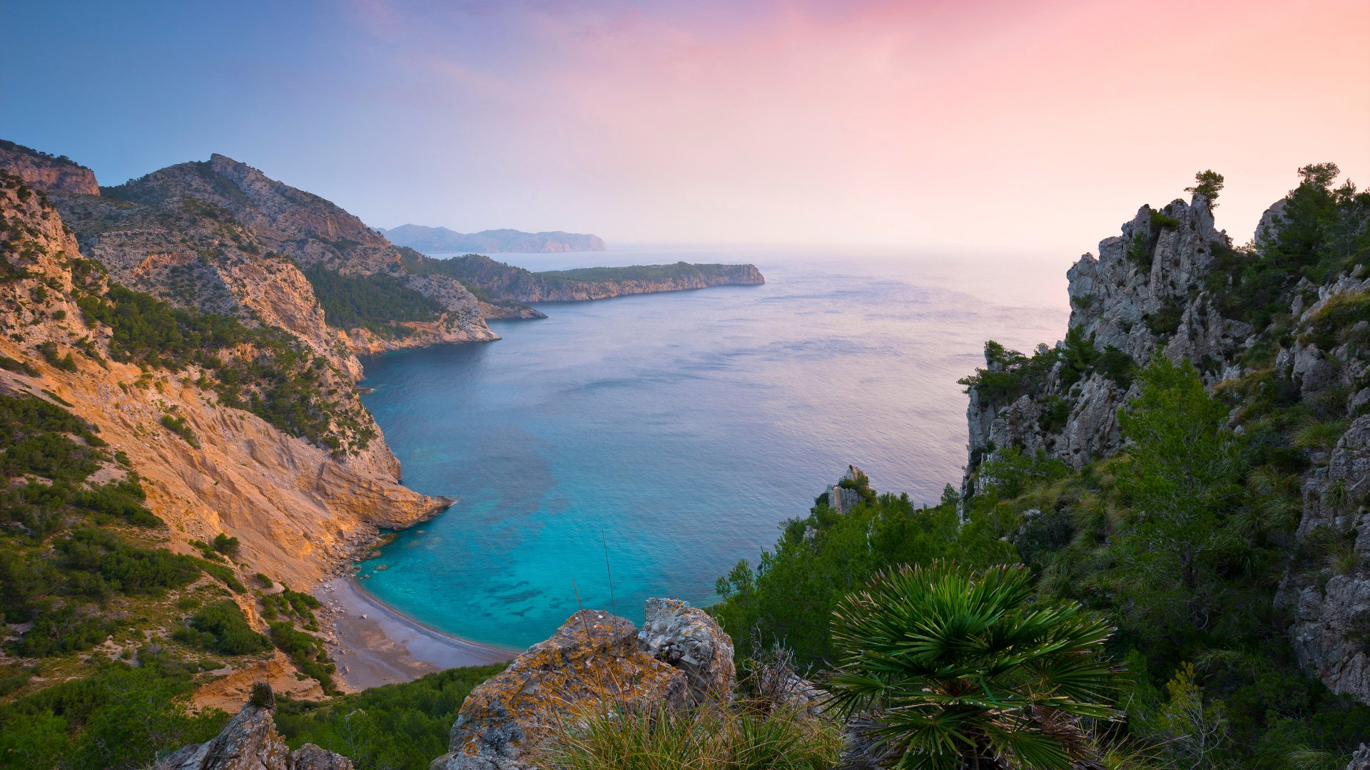 4K Ultra HD desktop wallpaper showcasing a serene coastline with a tranquil cove, surrounded by rugged cliffs and lush greenery under a soft pastel sky.