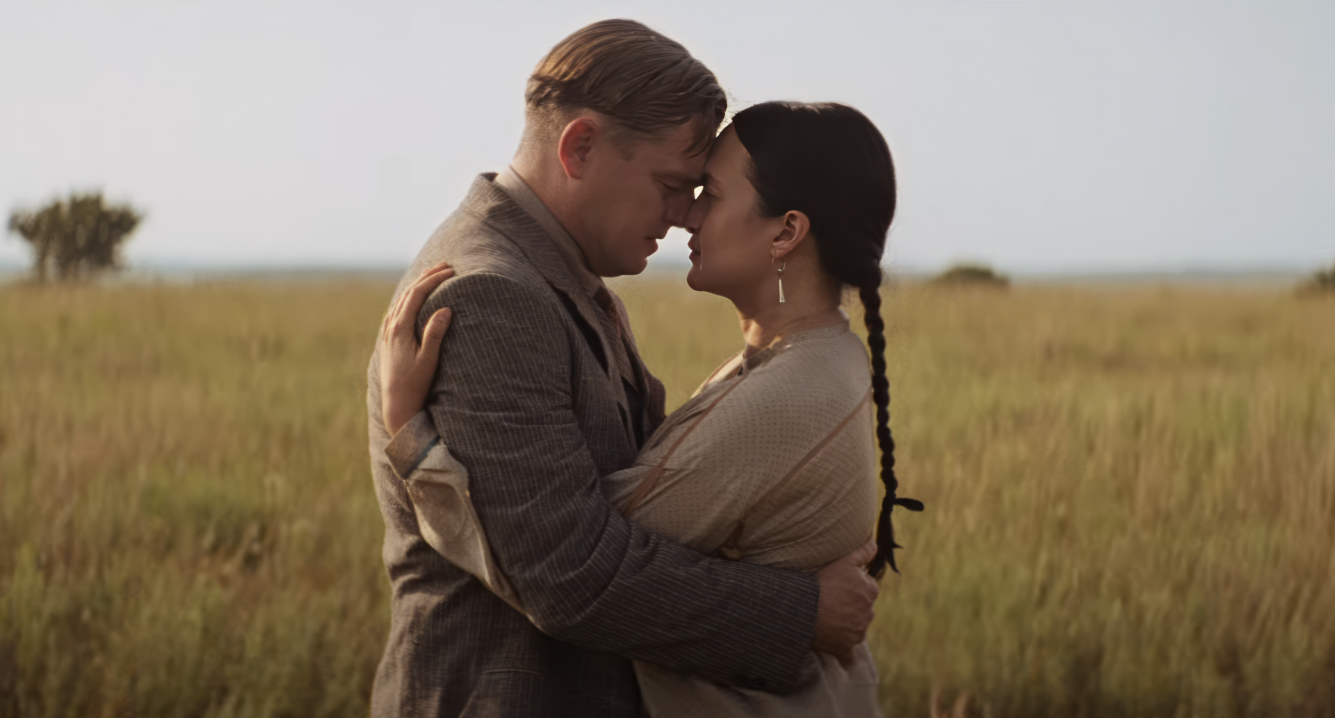HD wallpaper featuring a romantic scene with two characters embracing in a field from 'Killers of the Flower Moon' movie.