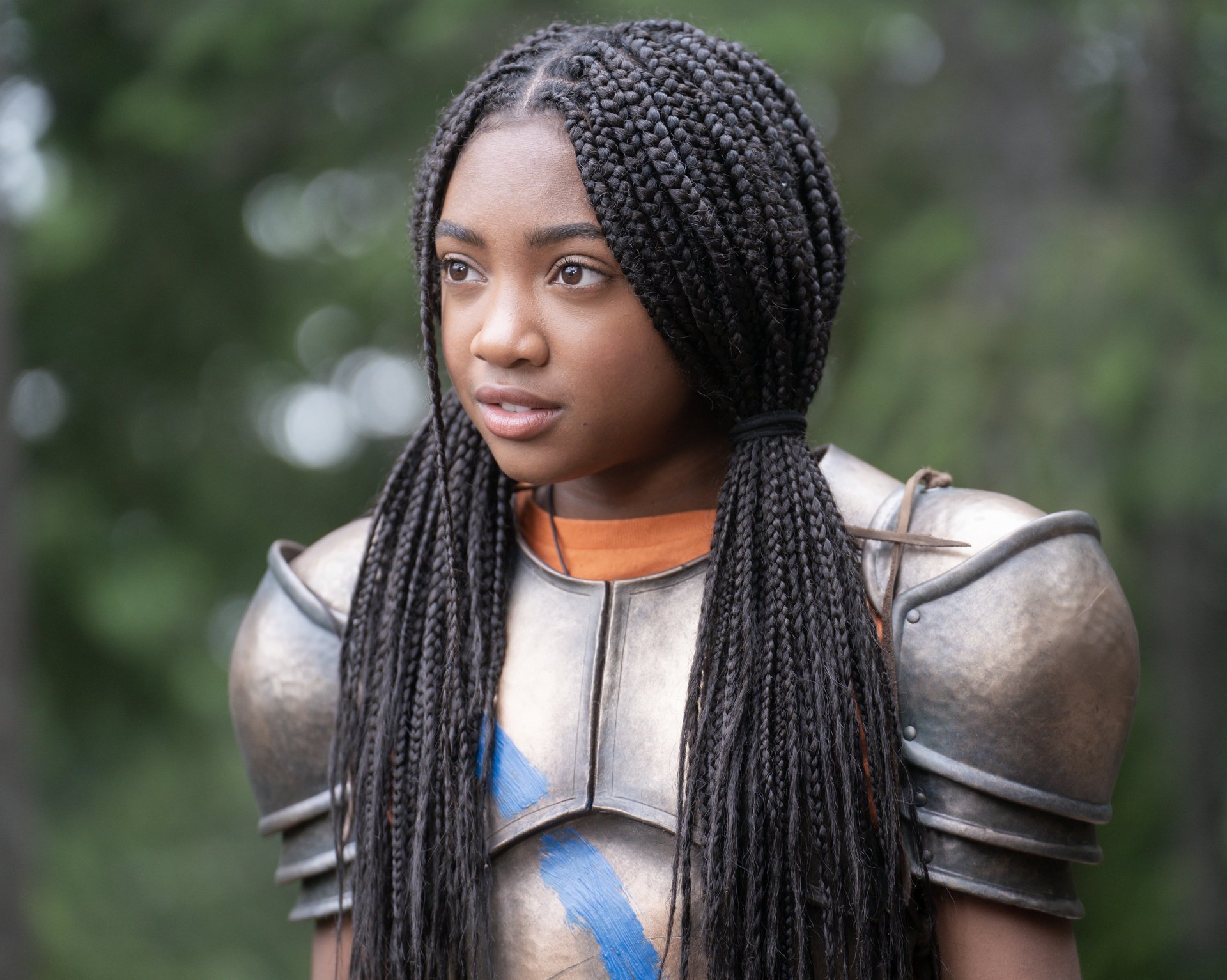 HD wallpaper of a character from the TV show Percy Jackson and the Olympians featuring a young female in armor with braided hair, set against a blurred natural background.
