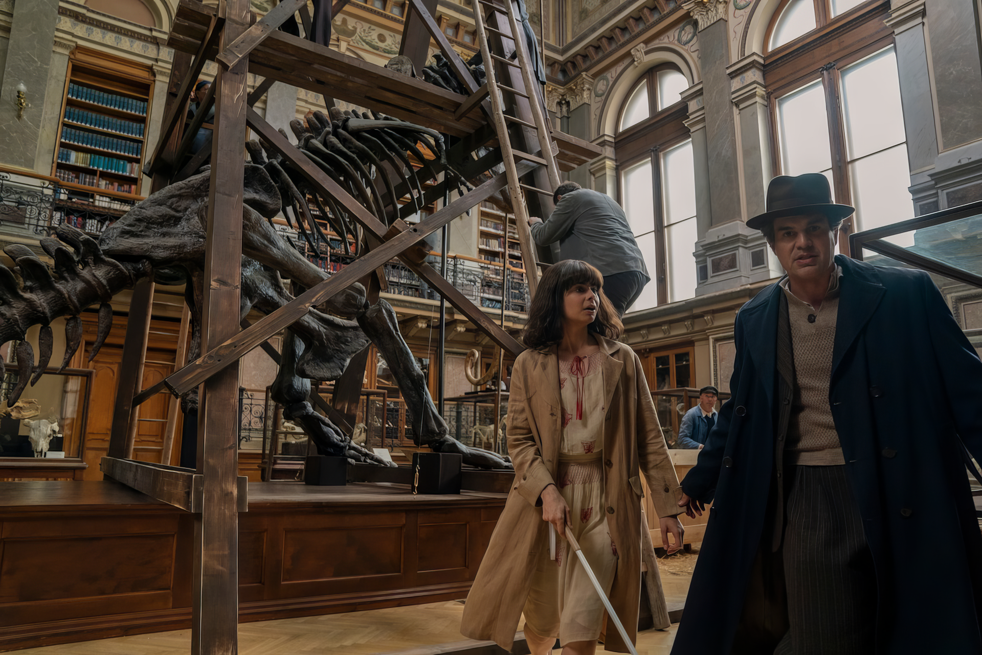 HD wallpaper featuring two characters from the TV show 'All the Light We Cannot See' walking through a museum with a dinosaur skeleton in the background.