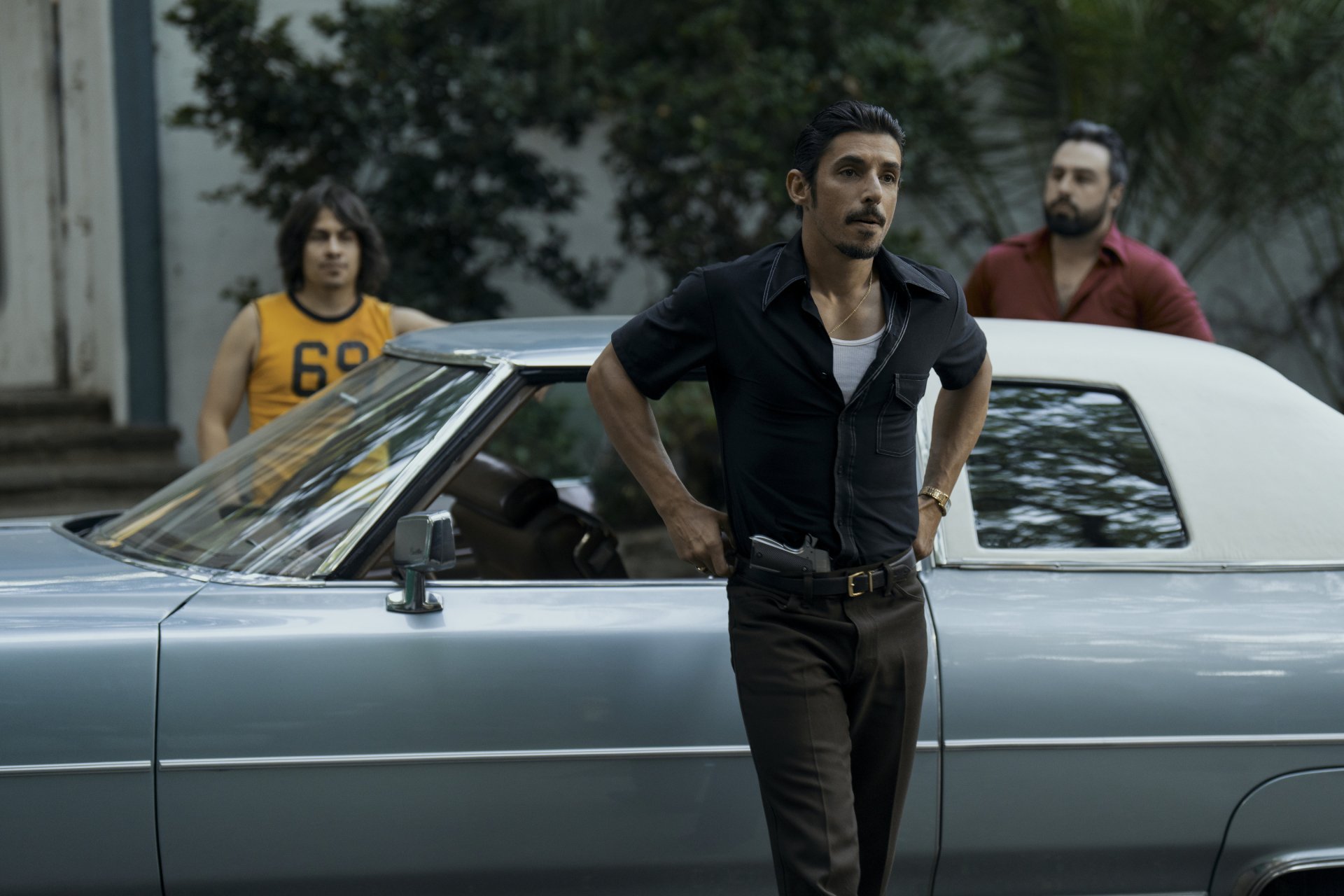 High-definition desktop wallpaper from the TV show Griselda (2024) featuring two men in a vintage car scene.