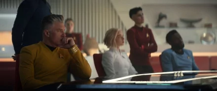 HD wallpaper featuring characters from Star Trek: Strange New Worlds, with a focus on a male officer in a yellow uniform thoughtfully seated at the forefront.