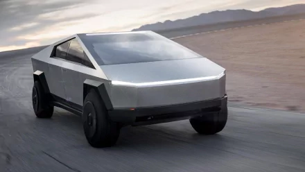 Tesla Cybertruck driving on a desert road, showcased as a high-definition desktop wallpaper and background.