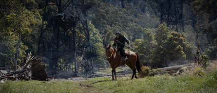 A scene from Kingdom of the Planet of the Apes, featuring a rider on horseback amidst a lush landscape, with towering structures and dense trees in the background.