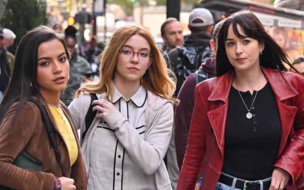 A striking HD wallpaper featuring Sydney Sweeney, Dakota Johnson, and Isabela Merced walking together, showcasing their stylish looks in an urban setting.