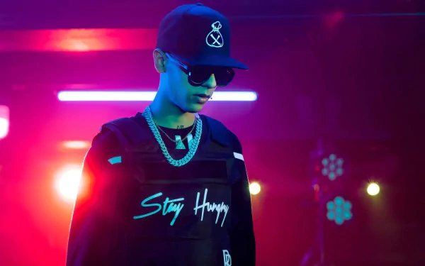 HD desktop wallpaper featuring a stylized image of a person with sunglasses and a baseball cap standing against a vibrant blue and purple neon light background, emblazoned with the slogan 'Stay Humble.'