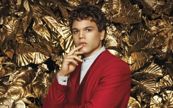 A contemplative individual in a red suit set against a golden foliage background themed around The Hunger Games: The Ballad of Songbirds & Snakes for HD desktop wallpaper.