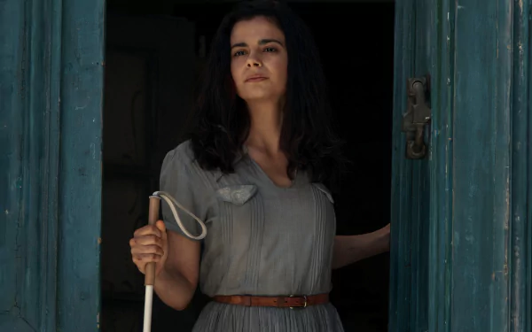 HD wallpaper featuring a scene from the TV show 'All the Light We Cannot See' with a woman holding a cane, standing in a doorway.