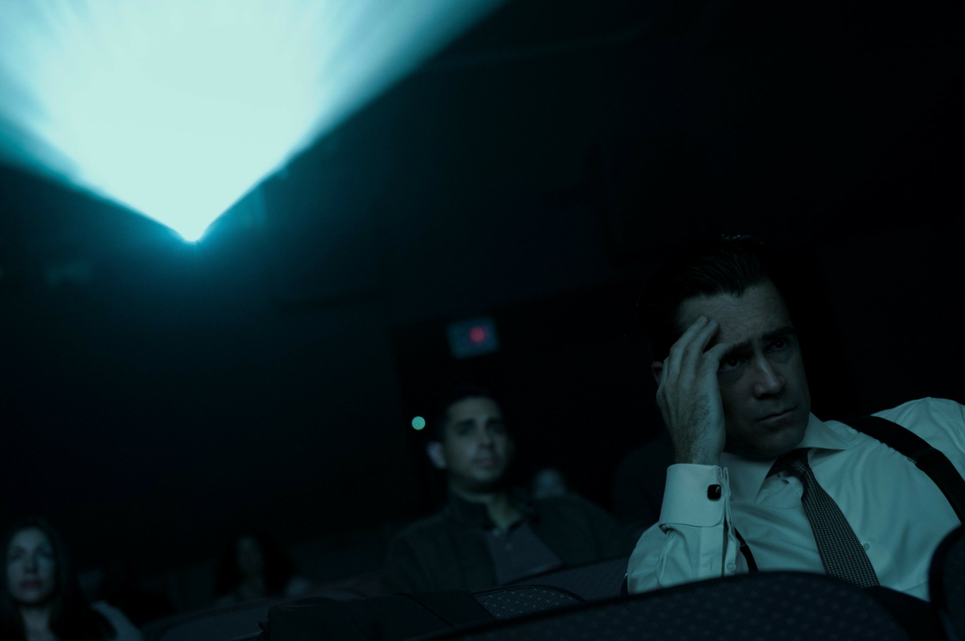 HD wallpaper featuring a tense scene from the TV show Sugar (2024) with a man in a white shirt appearing contemplative in a dimly lit cinema.