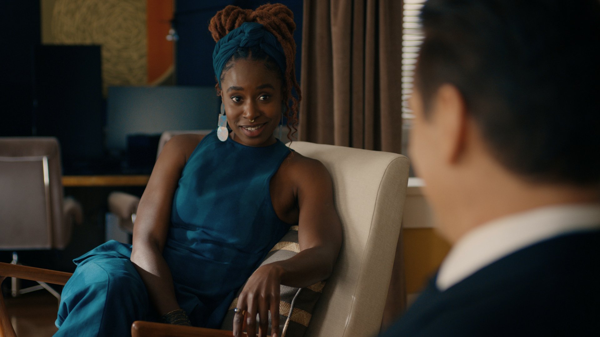 Kirby Howell-Baptiste in a scene from the TV show Sugar (2024), showcasing her in a stylish blue outfit, engaged in conversation in a modern setting. HD desktop wallpaper.
