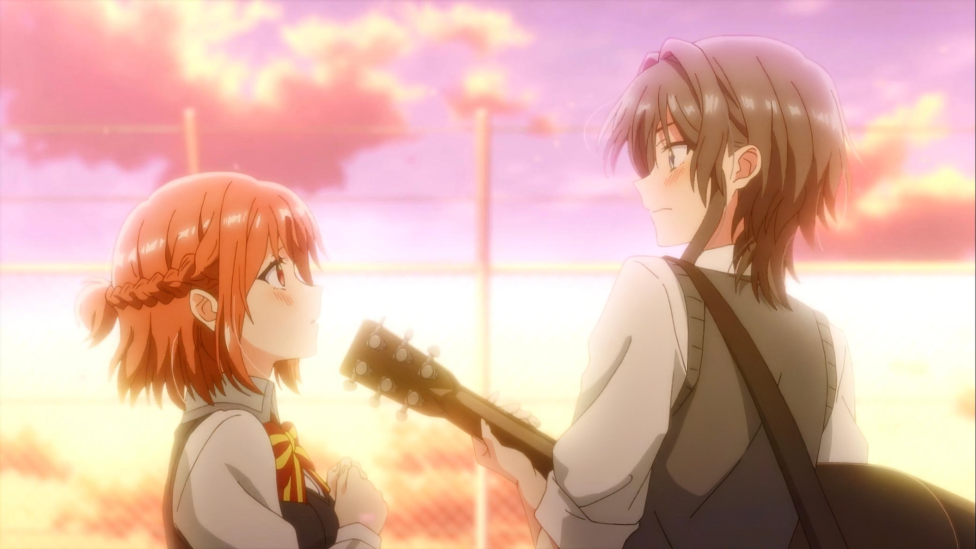 HD desktop wallpaper of two anime characters from Whisper Me a Love Song, featuring one character with short orange hair holding a guitar looking up at another character with longer hair, both bathed in the warm glow of a sunset background.