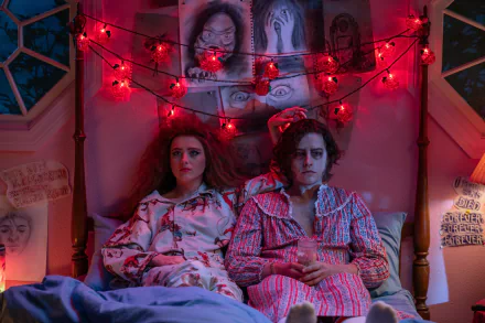 A scene from *Lisa Frankenstein*, featuring two characters in pajamas sitting together in a cozy bedroom adorned with red fairy lights, creating an intriguing atmosphere.