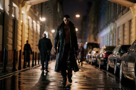 A moody scene from the movie The Crow (2024), featuring a brooding figure in a long coat walking down a rain-soaked street, surrounded by dimly lit buildings and passing pedestrians.