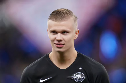 Professional soccer player in a black sports kit against a blurred stadium background, featured in a high-definition desktop wallpaper.