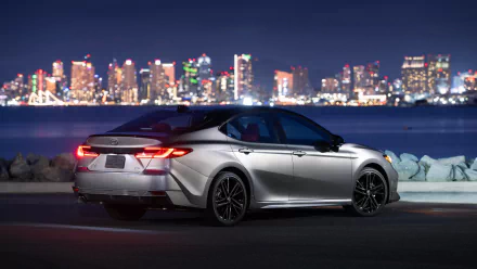 HD wallpaper of a Toyota Camry XSE parked with a night city skyline in the background.