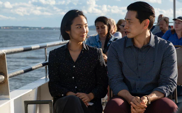 HD desktop wallpaper of two people from the movie Past Lives sitting together on a boat, with water and sky in the background.