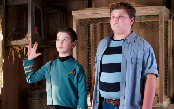 Young Sheldon HD wallpaper featuring two characters: one in a Star Trek uniform making a Vulcan salute and the other in a striped shirt, both standing in a rustic setting.