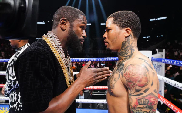 HD wallpaper of two boxers in a tense face-off inside a boxing ring, with one boxer heavily tattooed, indicative of a pre-fight promotional event.