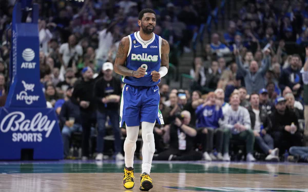 HD desktop wallpaper featuring a Dallas Mavericks basketball player on the court during a game, wearing a blue jersey with the team name and yellow sneakers. Fans are visible in the background.