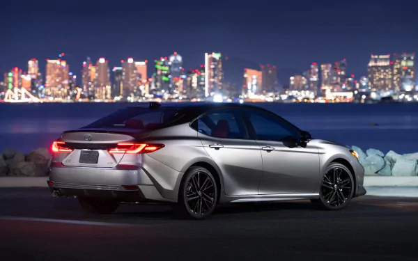 HD wallpaper of a Toyota Camry XSE parked with a night city skyline in the background.