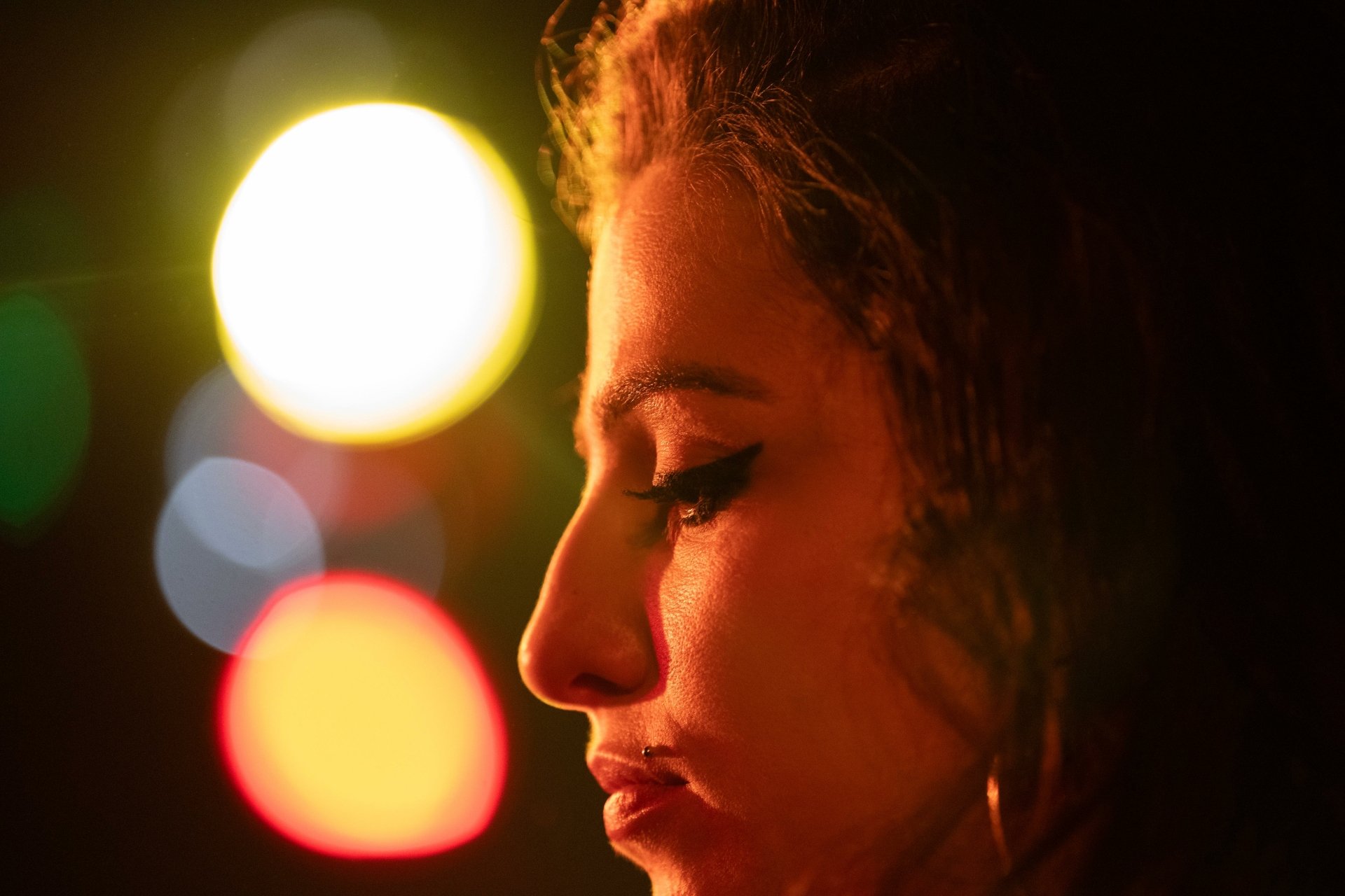 HD desktop wallpaper and background featuring a close-up profile of Amy Winehouse, tagged with movie and Back to Black, against a backdrop of colorful, out-of-focus lights.