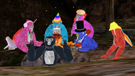 HD desktop wallpaper featuring colorful, cartoon-style gorillas from the video game Gorilla Tag sitting around a campfire in a rocky, forested environment.