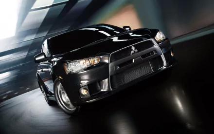 HD desktop wallpaper featuring a sleek black Mitsubishi Evolution X speeding through an urban environment at night.