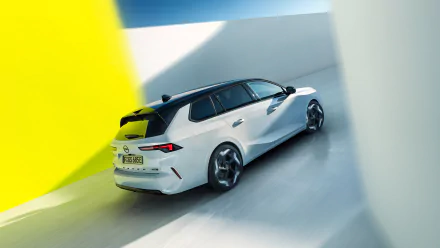 HD desktop wallpaper featuring a sleek white Opel Astra GSe, viewed from the rear, driving through a minimalistic, brightly lit space with contrasting yellow and white walls.