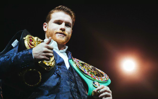 HD desktop wallpaper of a boxer in the ring, confidently holding championship belts with a spotlight in the background.