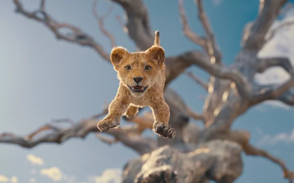 HD desktop wallpaper of a young lion mid-leap from The Lion King, set against a vivid blue sky and barren tree branches.