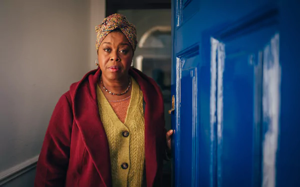 HD wallpaper featuring a woman from Doctor Who (2023) standing next to the iconic blue TARDIS door, expressing curiosity and concern.